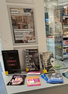 Bücher auf einem Tisch in der Stadtbücherei Glinde. Dazu ein Plakat mit der Aufschrift Lesen um Gewalt vorzubeugen
