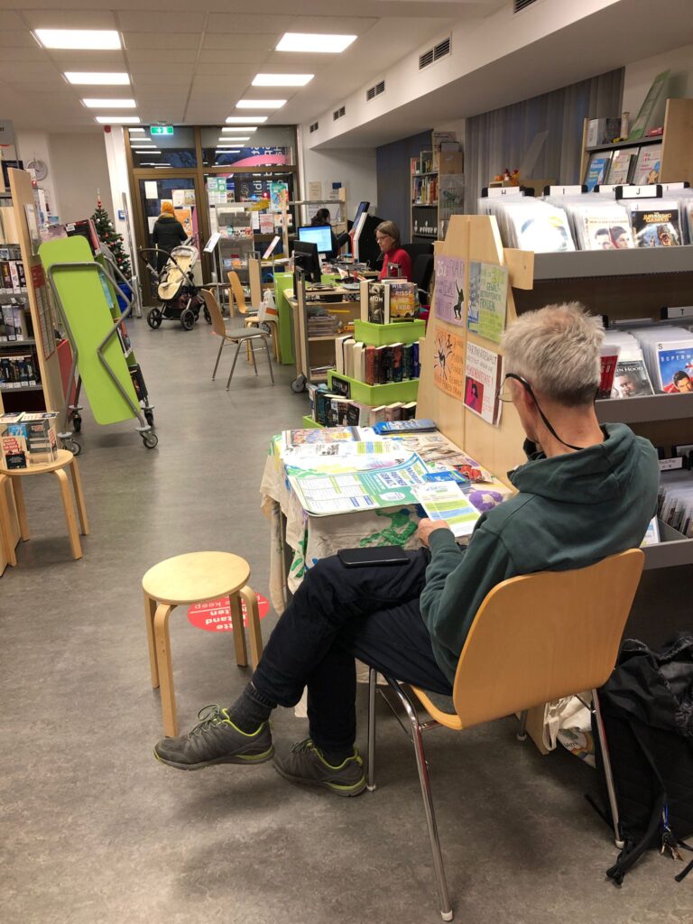 StoP-Aktiver sitzt am Infotisch in einer Bibliothek.