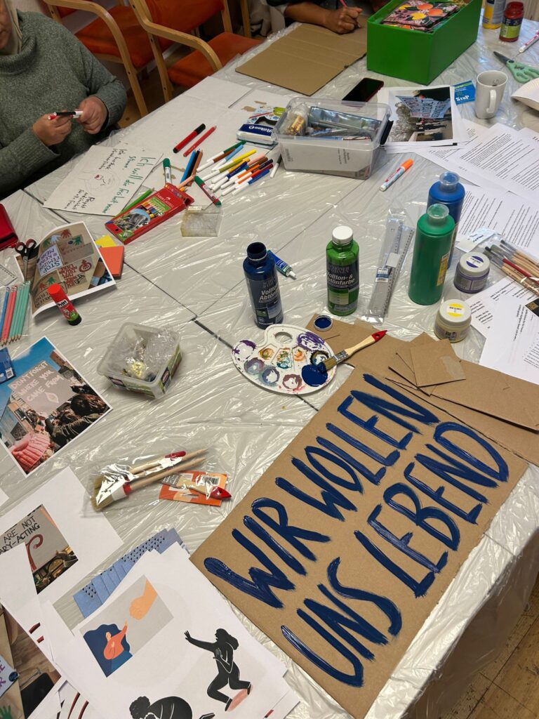 Selbstgemalte Schilder und Bastelmaterialien auf einem Tisch.