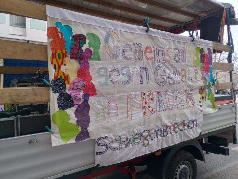 Ein besticktes Banner mit der Forderung: Gemeinsam gegen Gewalt an Frauen # SchweigenBrechen