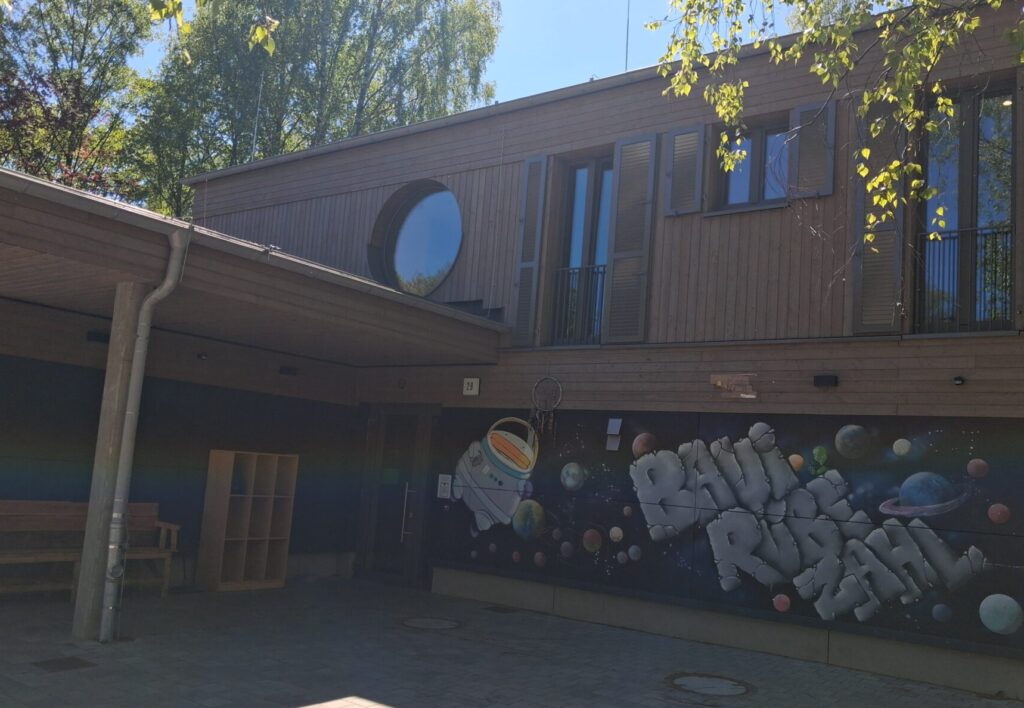 Den Eingangsbereich vom Bauihaus mit Schriftzug auf der Wand BAUI RÜBE ZAHL und ein stück vom Himmel