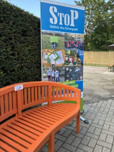 Orangefarbene Bank mit Hilfetelefon und StoP Roll-Up